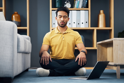 Meditation, laptop and a yoga man breathing for mental health, wellness or zen on the floor of his home. Fitness, internet and virtual class with a male yogi in the living room to meditate for peace