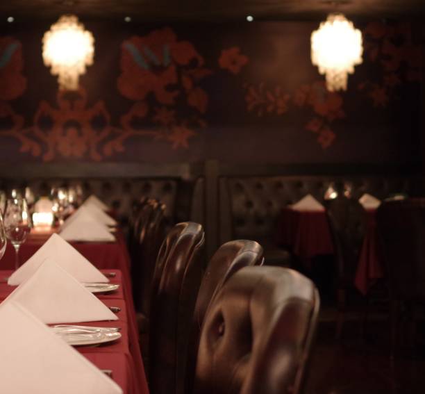 istock Folded white napkin and wine glasses on red tablecloth with candlelight and leather chairs 1618767720