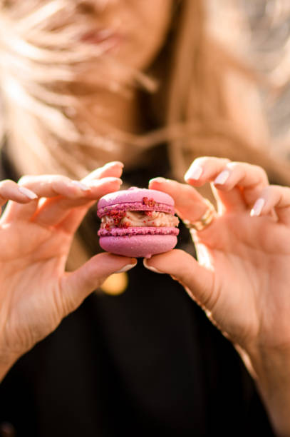 istock Selective focus on delicious pink macaron in female hands on blurred background 1618774523
