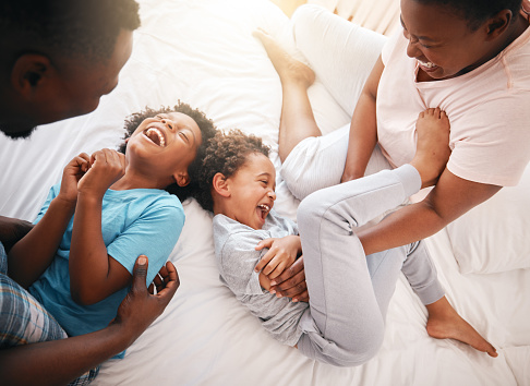 Tickle, funny and relax with black family in bedroom for bonding, playful and affectionate. Laugh, happiness and crazy with parents playing with children at home for wake up, morning and silly
