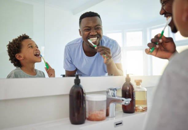 istock Dental, brushing teeth and father with son in bathroom for bonding, morning routine and cleaning. Teaching, self care and toothbrush with black man and child at home for wellness, fresh and hygiene 1618796536