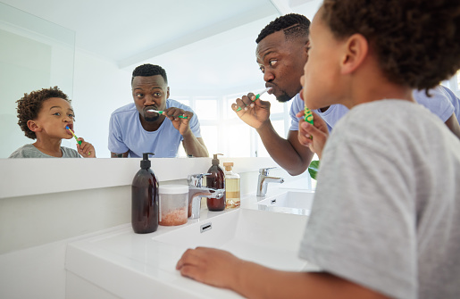 Learning, brushing teeth and father with son in bathroom for dental, morning routine and cleaning. Teaching, self care and toothbrush with black man and child at home for wellness, fresh and hygiene