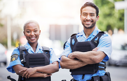 Happy, portrait and police with arms crossed in the city for security, safety and justice on the street. Team, pride and a black woman and a man with confidence working in urban crime together