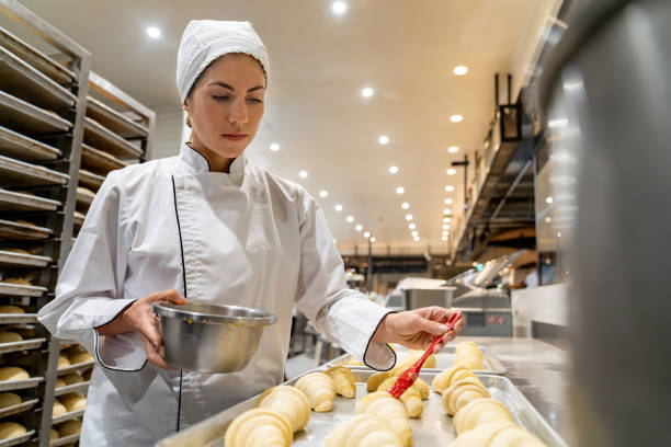 istock Baker spreading egg yolks on some croissants before putting them in the oven 1618826208