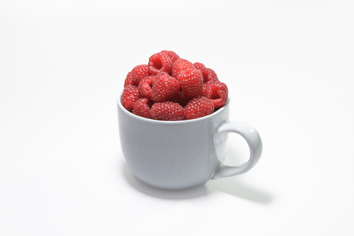 Filled large gray mug, with fresh raspberries on a white background
