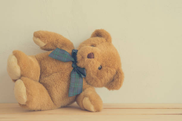 Cute brown teddy bear doll sitting with white wall background copy space. Children toy, learning concept.