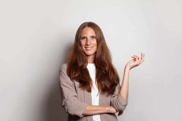istock Nice confident businesswoman showing empty palm hand against white studio wall background 1618911542