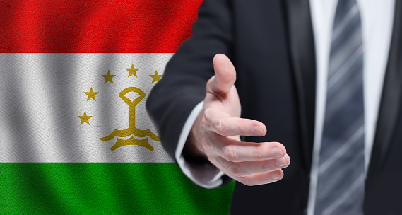 Tajik business, politics, cooperation and travel concept. Hand on flag of Tajikistan background.