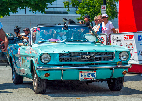 Halifax, Nova Scotia, Canada -  July 1, 2018 :  Team 25 - 1964 1/2 Ford Mustang convertible from Mobile, Alabama with a male driver and female passenger, Hemmings Motor News Great Race 2018, Lower Water Street, Halifax, NS, Canada.