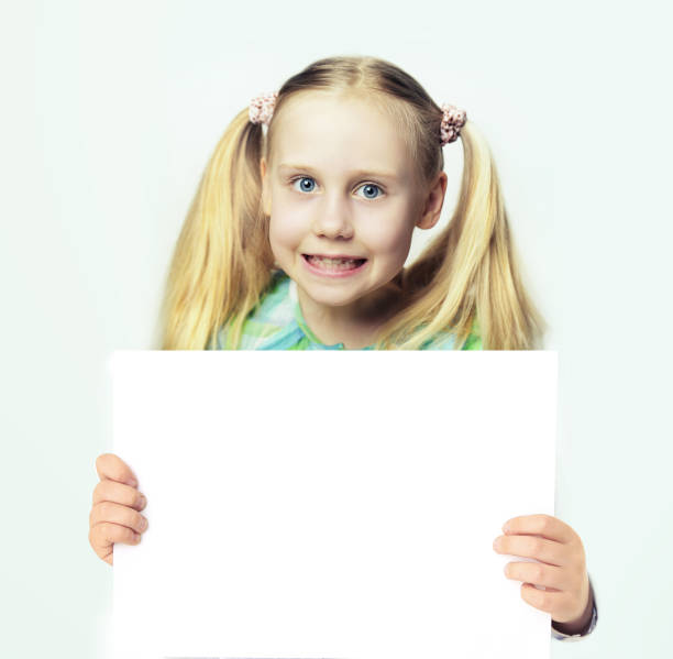 istock Funny kid showing white empty blank paper banner board with copy space 1618933237