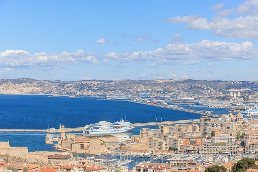 A scenics aerial view of the city of Marseille, bouches-du-rhône, France with a cruise ship arriving at the port under a majestic blue sky and some white clouds on March 24, 2023 in Marseille, bouches-du-rhône, France