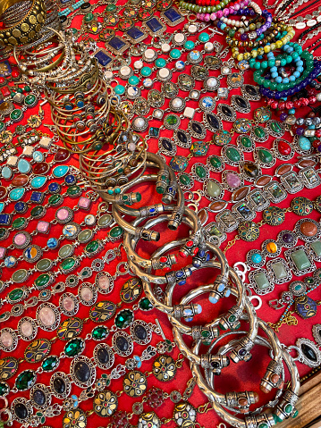 Stock photo showing close-up, elevated view of a collection of jewellery including bangles, beaded wristbands and bracelets, ready for sale at an outdoor market stall.