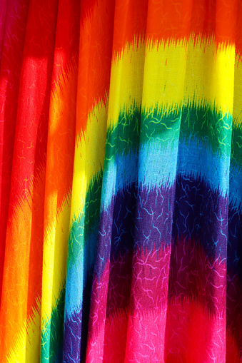Stock photo showing close-up view of outdoor market display of hanging colourful rainbow sarong fabric.