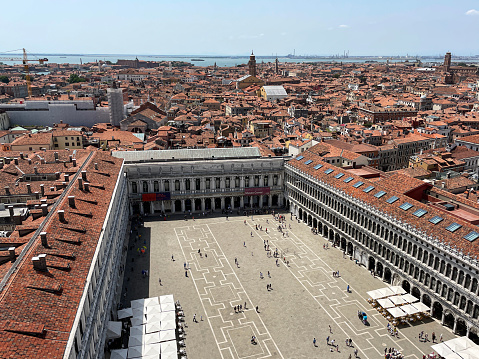 Stock photo showing close-up view of Piazza San Marco (St. Mark's Square), Museo Correr, al freco dining cafes and terracotta rooftops of residential buildings viewed from St Mark's Campanile (bell tower).