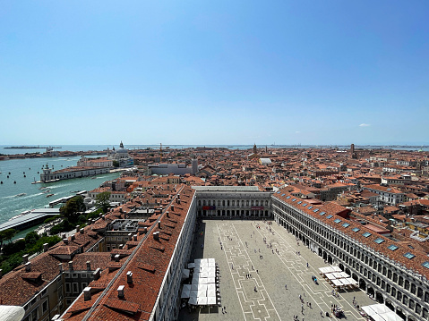 Stock photo showing close-up view of Piazza San Marco (St. Mark's Square), Museo Correr, Giardini Reali di Venezia (Royal Gardens of Venice), Le Zitelle, al freco dining cafes and terracotta rooftops of residential buildings viewed from St Mark's Campanile (bell tower).