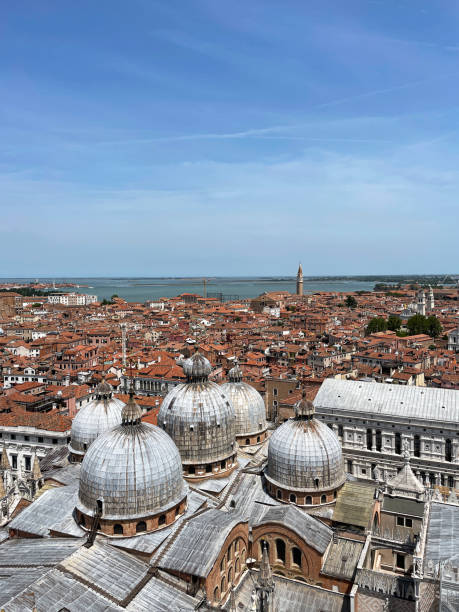 Stock photo showing close-up view of Basilica di San Marco (St Mark's Cathedral) domes, Bell tower of the Oratorio San Marco in Vinea, Palazzo Ducale (Doge's Palace) and terracotta rooftops of residential buildings viewed from St Mark's Campanile (bell tower). imagen del paisaje urbano de venecia, italia, vistas desde el campanile de san marcos (campanario) de las cúpulas de la basílica de san marco (catedral de san marcos), campanario del oratorio san marco in vinea, palazzo ducale (palacio ducal), tejados, c