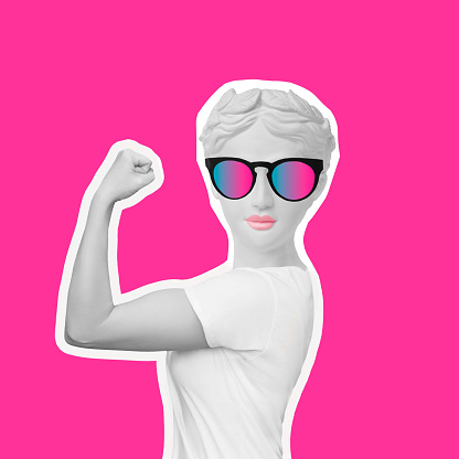 Strong smiling woman headed by antique statue in sunglasses raises arm and shows bicep on a pink color background. Support women rights, feminism. Trendy collage in magazine style. Contemporary art
