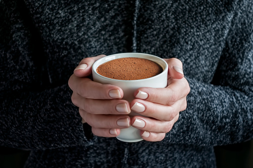 woman covered in blanket holding a cup of hot chocolate