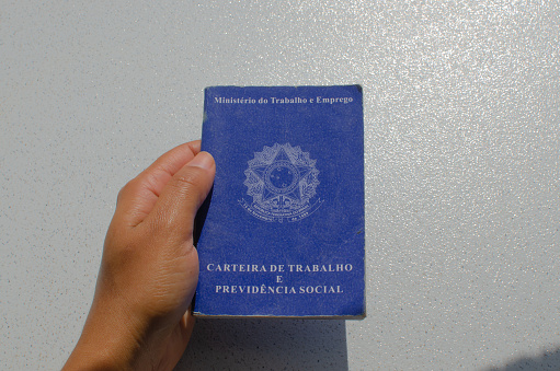 Brazil Work Card - Hand holding the Carteira de Trabalho do Brasil, an essential labor document that records information about FGTS, INSS, unemployment, salary, CTPS and CLT.