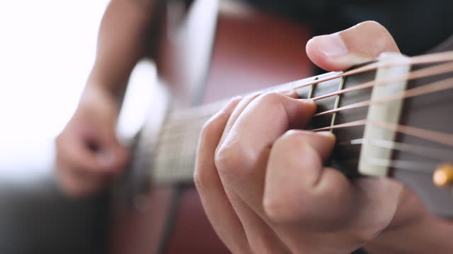 Close up a man playing guitar indoors