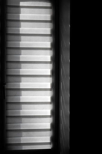 A vertical window with horizontal texture and shadows in a dark room
