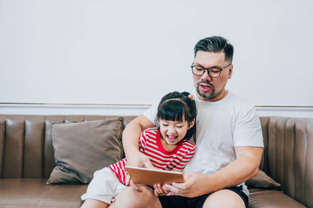 istock Girl and Dad Playing Tablets Together 1619045401
