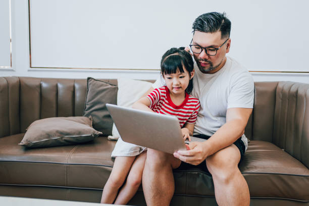 istock Daughter Watches Dad Work on a Computer at Home 1619046613