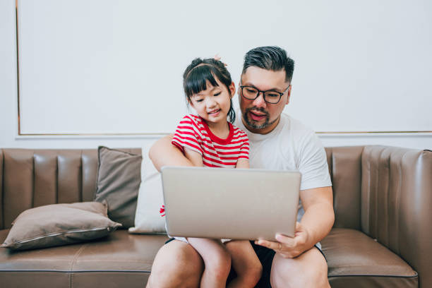 istock Daughter Watches Dad Work on a Computer at Home 1619047035