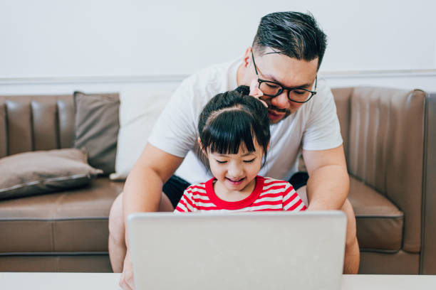 istock Daughter Watches Dad Work on a Computer at Home 1619047062