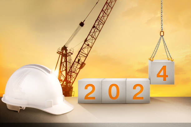 istock engineer working table and silhouette of construction-crane and golden sky for preparation of welcome 2024 new year party and change new business. 1619057762