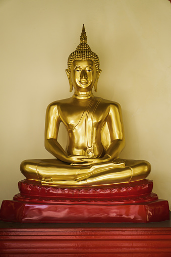 A beautiful of a golden Buddha statue sitting on a red base.