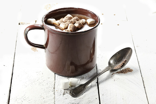hot chocolate drink in a vintage enamel mug on wooden background