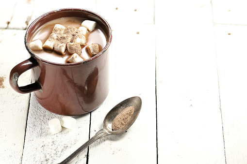 hot chocolate drink in a vintage enamel mug on wooden background