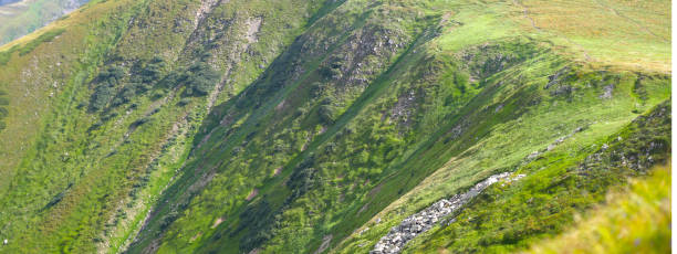 mountain landscape with grass and shrubbery and steep slopes.