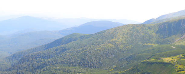 berglandschaft mit grün und blauem himmel mit wolken und dunstigem horizont. - sky blue grass green stock-fotos und bilder