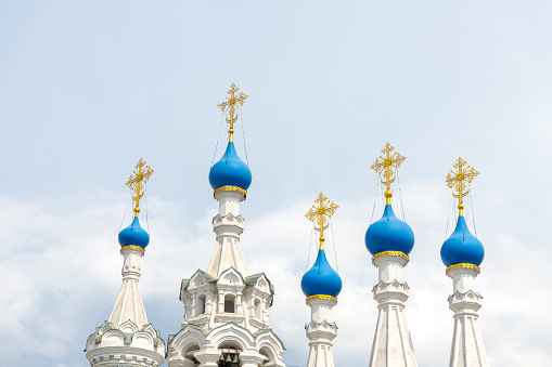 Close-up view of blue cupolas with golden crosses of Russian Orthodox Nativity Church at Putinki in Moscow against cloudy sky in a summer day. Copy space for your text. Religious architecture theme.