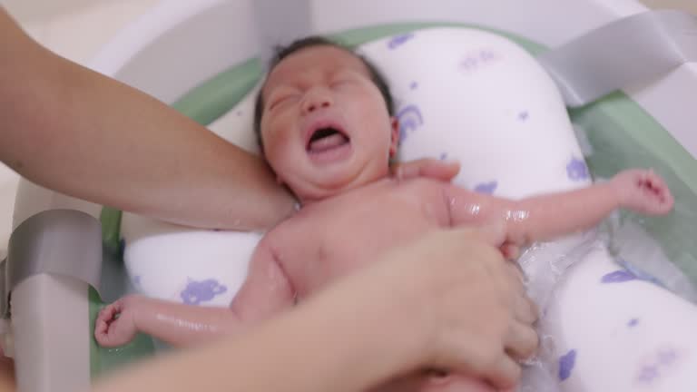 The newborn baby cried while taking a shower