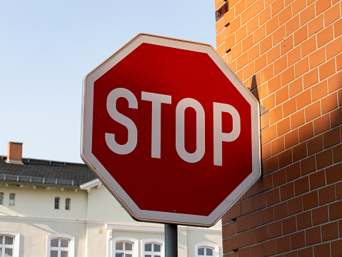 STOP traffic sign next to a building exterior in Germany. Drivers must stand still and give priority to other road users.