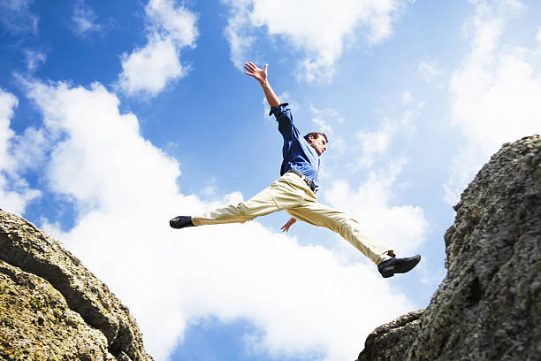 Businessman jumping over the mountains stock photo