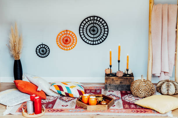 istock Decorated cozy autumn interior for relax during fall holidays. Comfy floor location with cushions, wicker pumpkins, burning candles. Thanksgiving, Halloween plans at home. Romantic date, movie night 1619205712