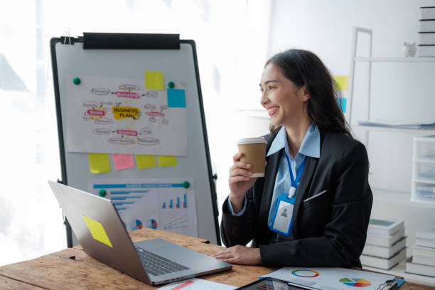 istock Asian Businesswoman Using laptop computer and working at office with calculator document on desk 1619213212
