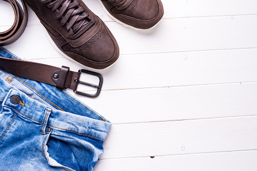 male jeans, belt and shoes on wooden background with text space, top view