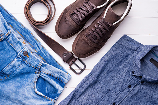 blue male jeans and shirt with brown belt and shoes, top view