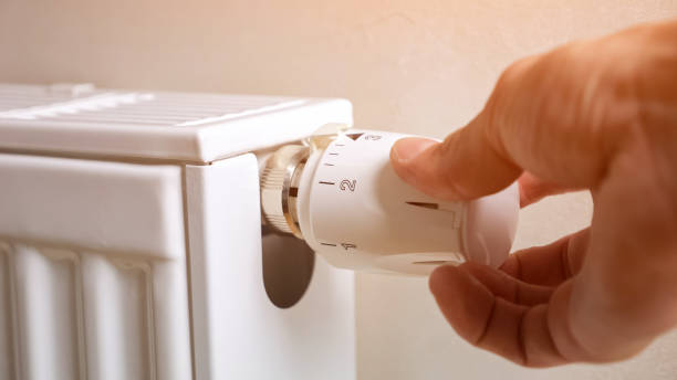 istock Man hand regulates temperature on radiator in premise 1619260966