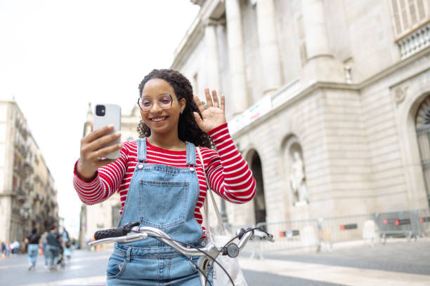 istock Young woman with a bicycle using smart phone and taking selfie 1619279838