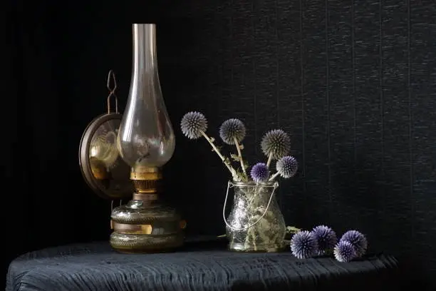 Rustic arrangement with a gas lamp and a vase with glandular globe-thistles