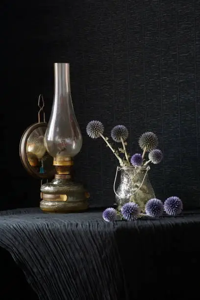 Rustic arrangement with a gas lamp and a vase with glandular globe-thistles