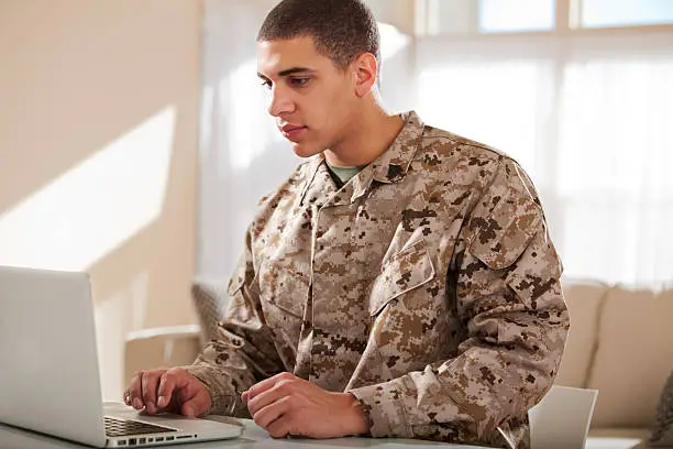 US Marine Corps soldier working on laptop. The model is wearing an official US Marine corps Marpat BDU uniform.
