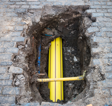 A newly installed gas pipe, buried deep below older pipes under a cobbled street.