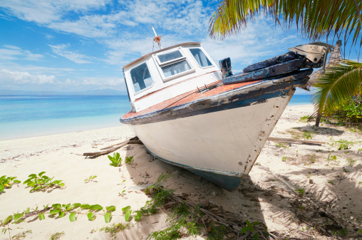 A small boat in a bad condition marooned on the beach of a small Fijian island off the coast of Viti Levu.